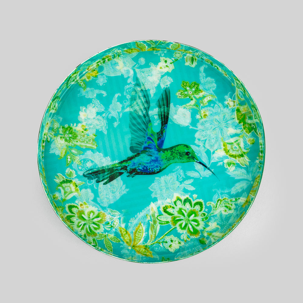 "Close-up of hummingbird in flight with white hibiscus flowers on turquoise
decorative iron serving tray"