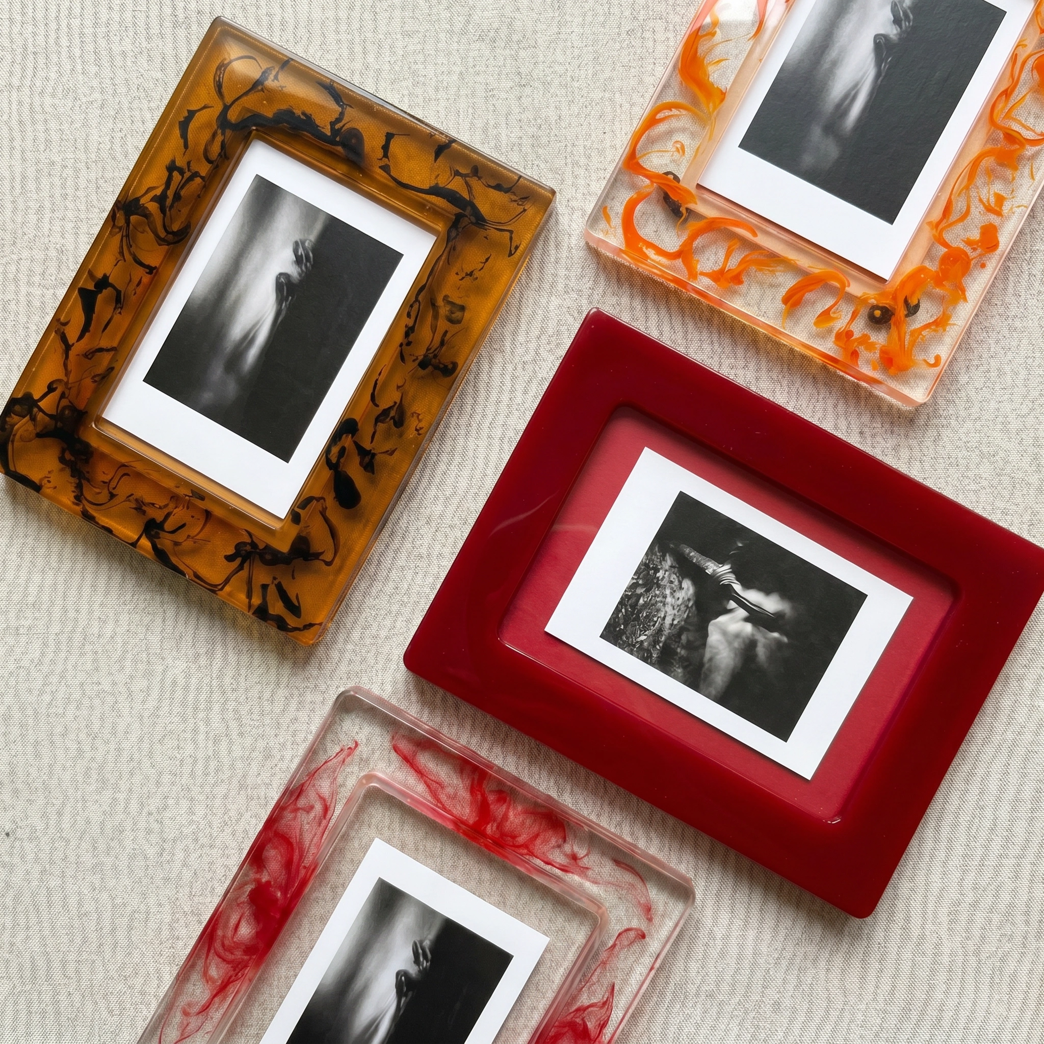 "Tyetye resin picture frames with abstract ink-swirl patterns in amber, red, and orange colorways