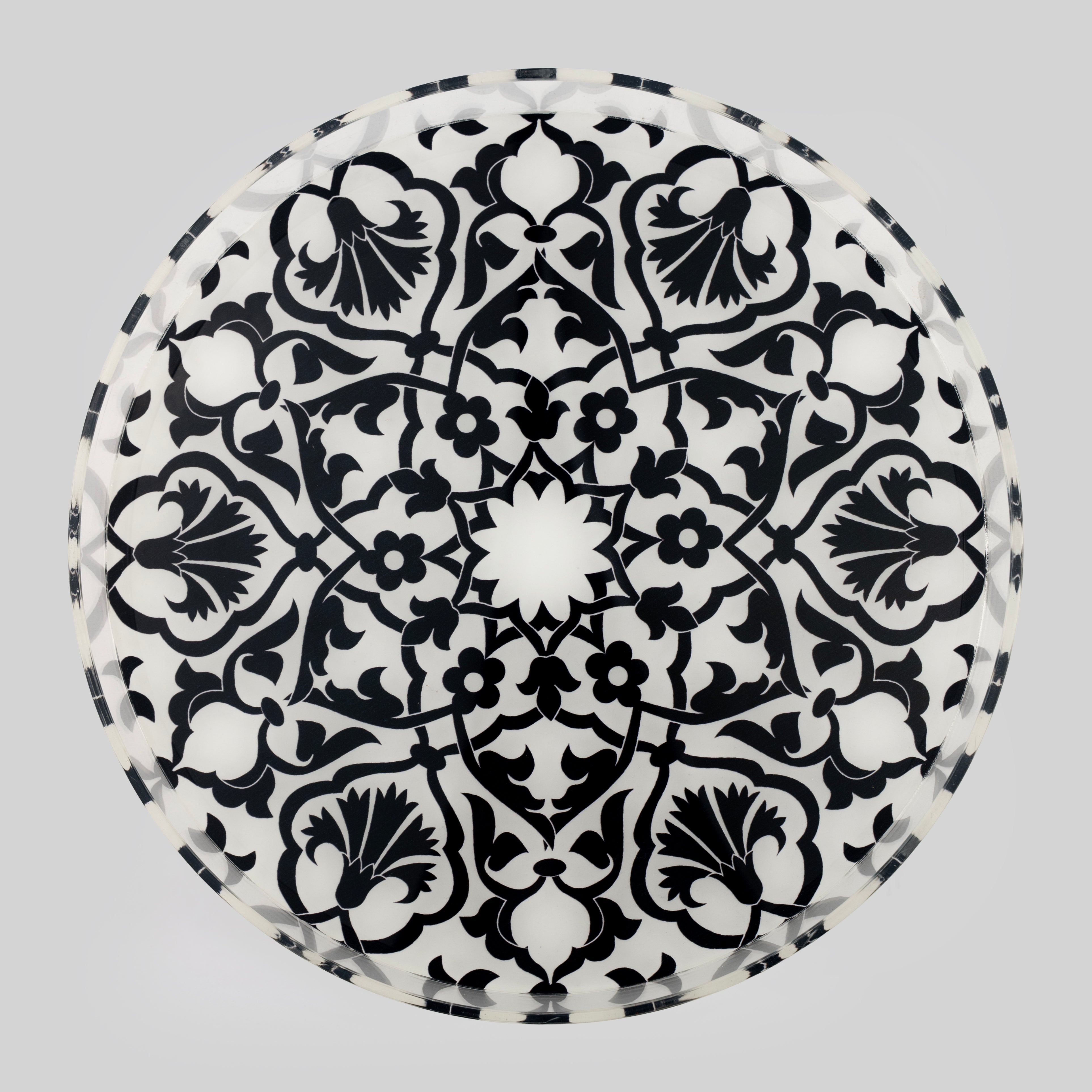 Round Ottoman print tray in black and white, featuring an Iznik-style radial pattern of tulips, carnations, cloud scrolls and a central geometric star, with a faceted rim.