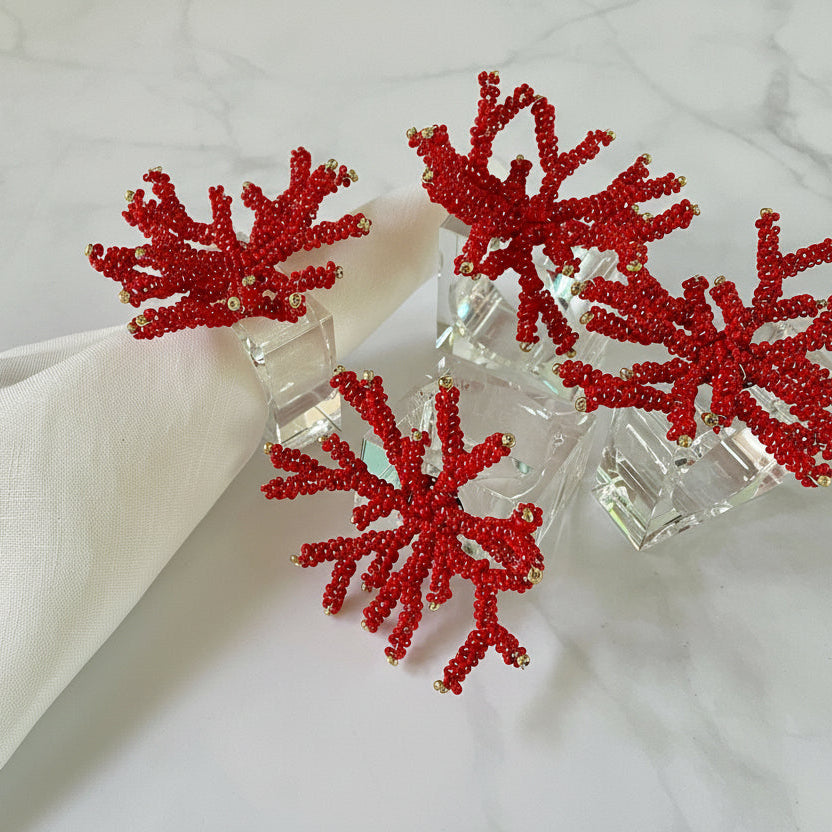 Hand-beaded red coral napkin rings on a lucite base, adding vibrant elegance to table settings.