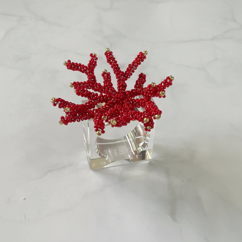 Hand-beaded red coral napkin rings on a lucite base, adding vibrant elegance to table settings.