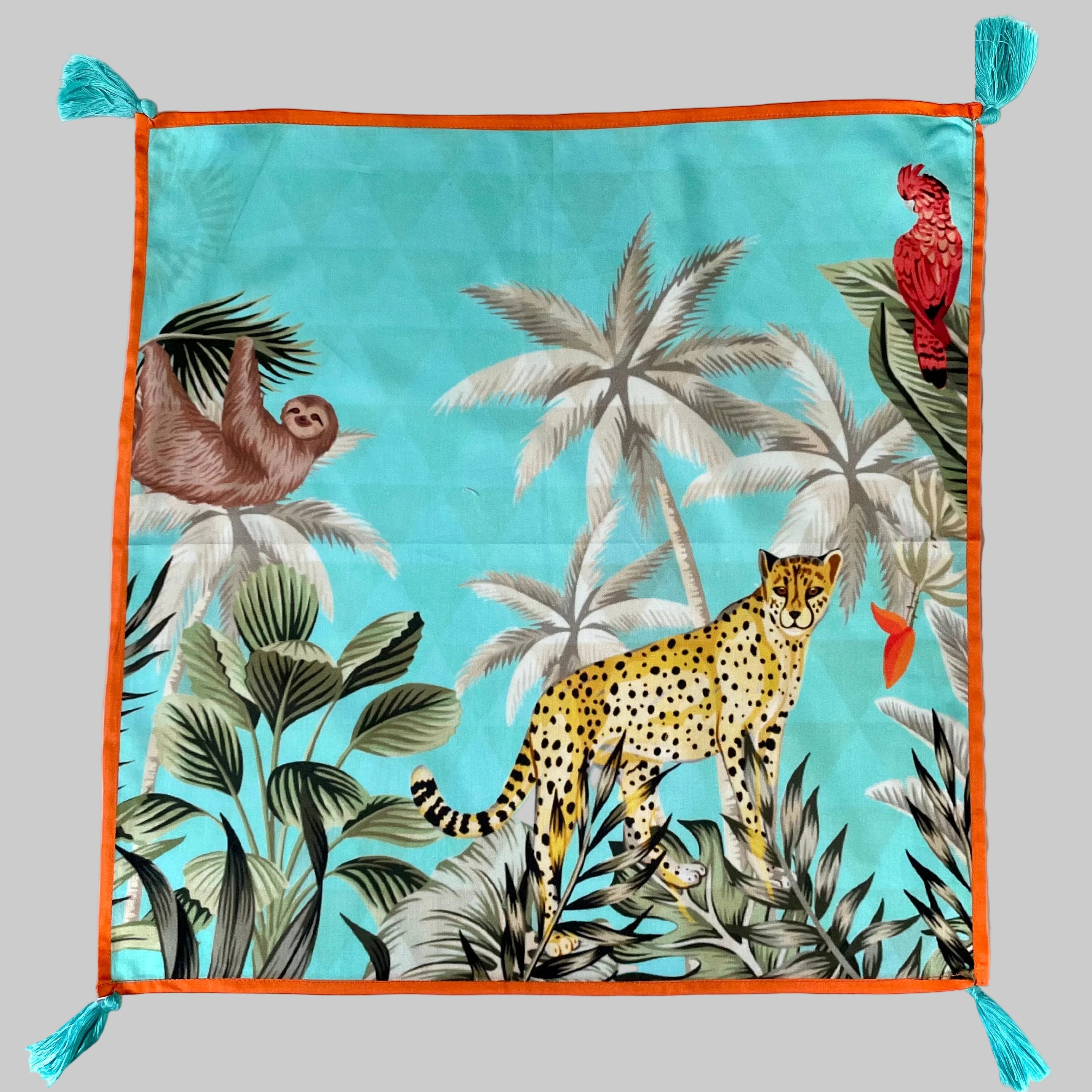 Set of four white cotton napkins with colorful tropical safari animal print pattern and decorative tassel trim, 17 inch square dinner napkins