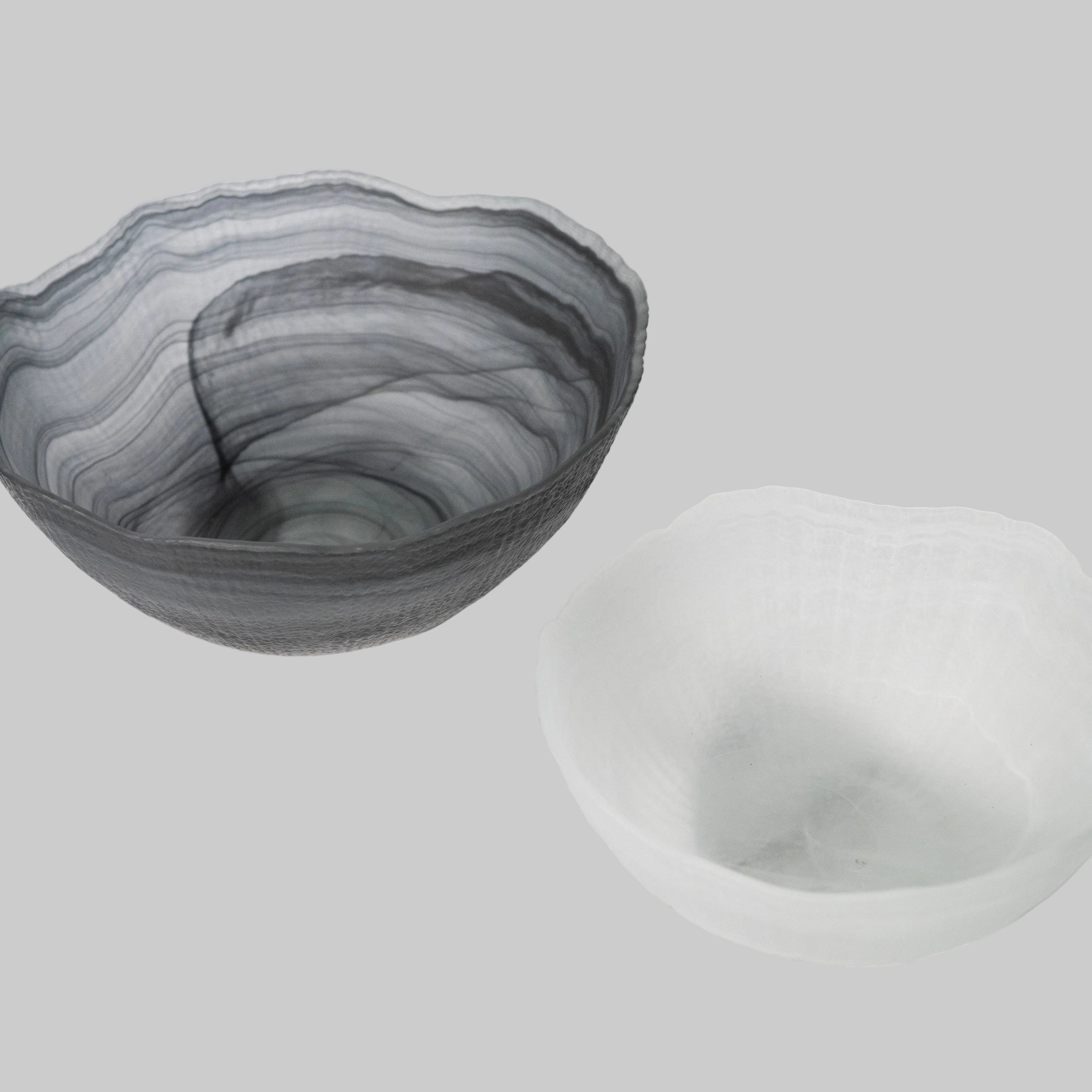 "A collection of sculptural glass bowls, showcasing unique shapes and vibrant colors, elegantly arranged on a decorative surface."