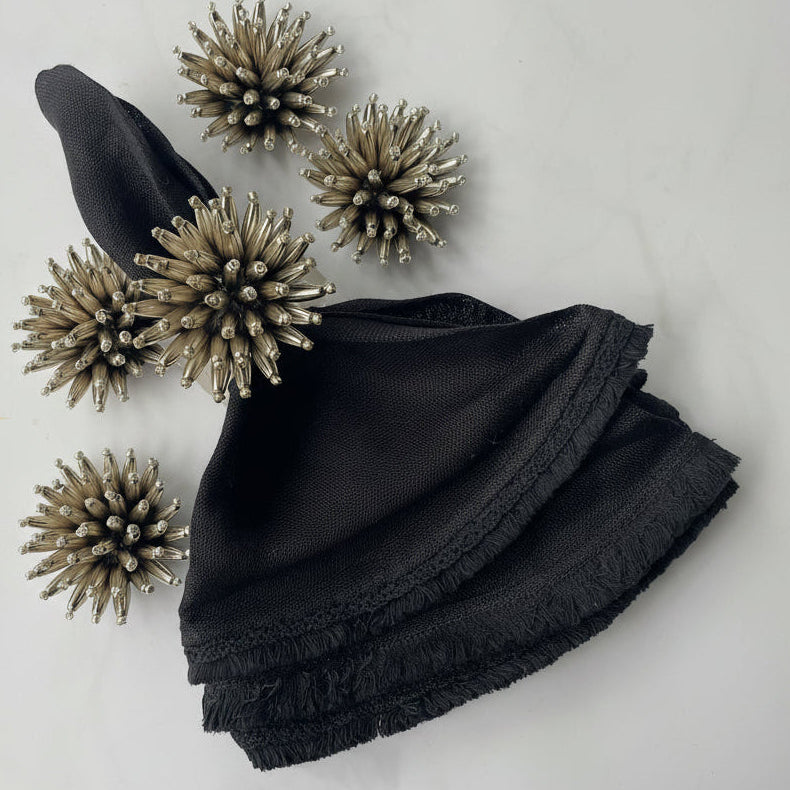 Hand-beaded black and silver napkin rings with a floral design on a lucite base, adding a modern touch to table settings.